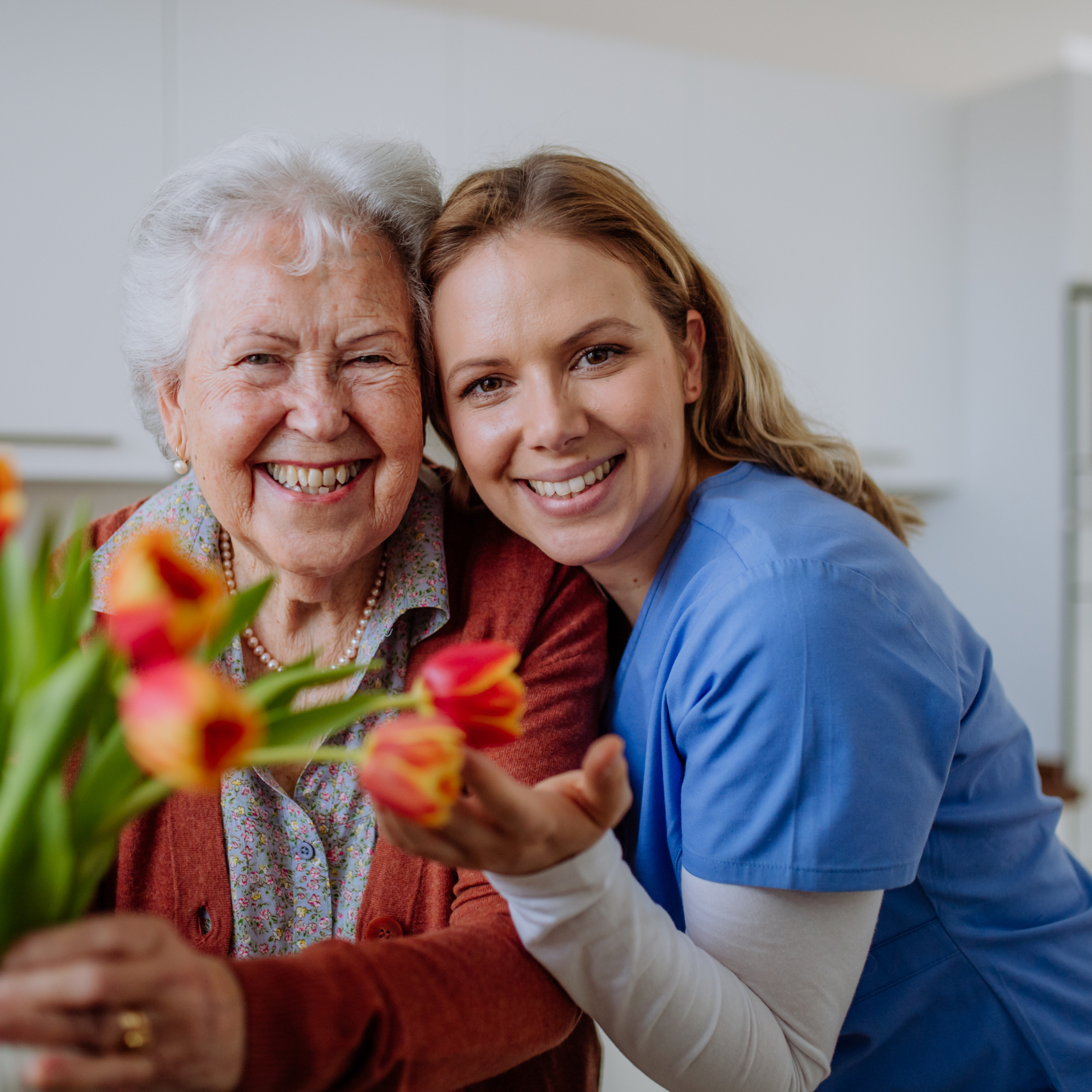 Senior woman and nurse with a tulip bouquet.